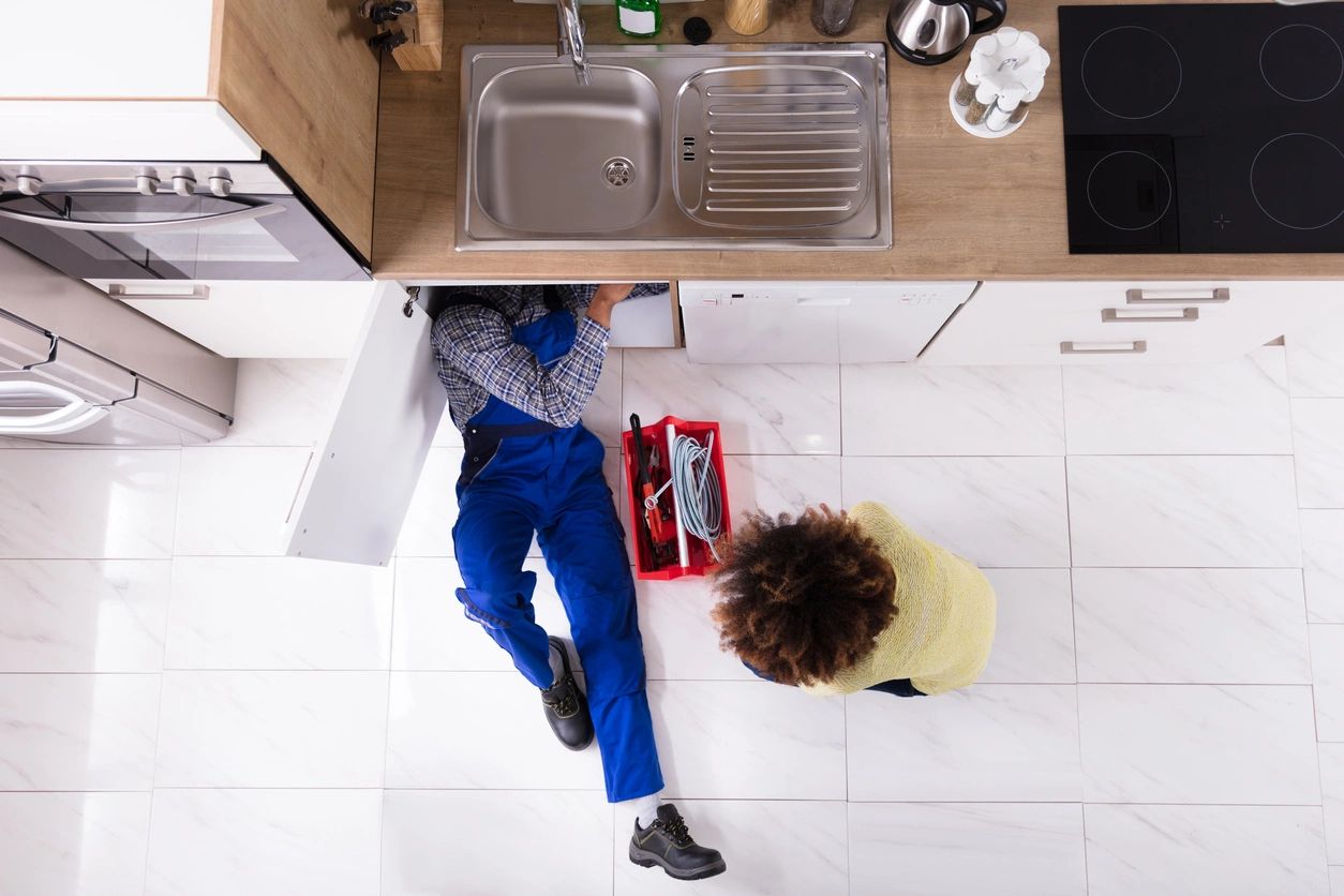 A person sitting on the floor next to a sink